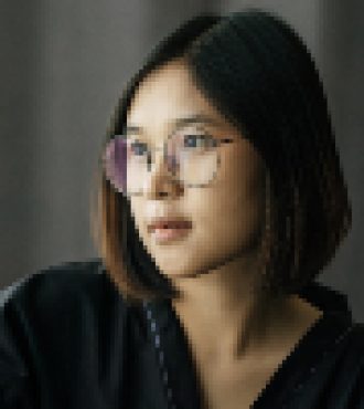 Woman wearing a black coat, wearing glasses, sitting, pressing the remote control to turn on the air.